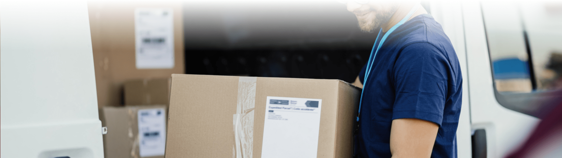 Persona manipulando cajas de envío sobre una carretilla durante un proceso de logística y distribución.